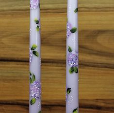 two white candles with purple flowers on them