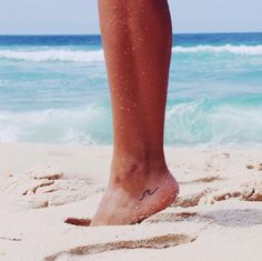 a person standing in the sand at the beach with their foot sticking out from the sand