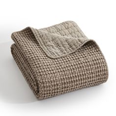 a blanket is folded on top of a white surface with a light brown checkered pattern