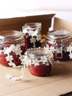 four jars filled with jam sitting on top of a cardboard box