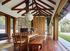 a dining room with wooden tables and chairs next to an open floor plan that has wood beams on the ceiling