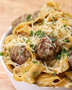 pasta with meatballs and parmesan cheese in a white bowl on a wooden table