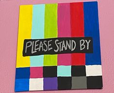 there is a sign that says please stand by on the side of a pink wall