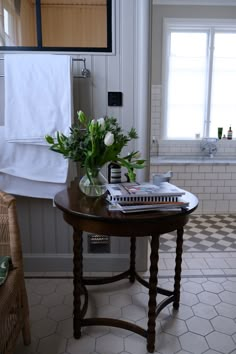 a table with flowers and books on it in a bathroom