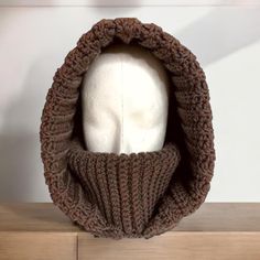 a white mannequin head wearing a brown knitted hood