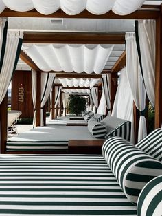 an indoor area with striped rugs and white drapes on the ceiling, along with black and white furniture