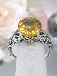 Natural Yellow Citrine Sterling Silver Ring Swan Design #D190 Introducing our Natural Yellow Citrine Swan Ring, D190, an exquisite piece that effortlessly blends elegance with vintage charm. Crafted with meticulous attention to detail, this Art Deco-inspired ring features a stunning natural yellow citrine gemstone nestled within a sterling silver filigree setting. At the heart of this ring is a full cut oval citrine, measuring 12mm in length and 10mm in width, radiating warmth and vibrancy. The Formal Oval Yellow Topaz Ring, Formal Yellow Oval Topaz Ring, Formal Yellow Topaz Ring With Accent Stones, Yellow Sapphire Topaz Ring For Wedding, Elegant Yellow Sapphire Topaz Ring With Accent Stones, Formal Citrine Solitaire Jewelry, Yellow Topaz Ring With Center Stone For Formal Occasions, Formal Solitaire Citrine Jewelry, Classic Yellow Topaz Ring For Formal Occasions