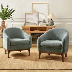 two blue chairs sitting next to each other on top of a wooden floor in front of a potted plant