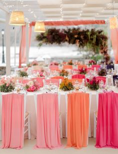 the tables are decorated with pink, orange and white linens for a wedding reception