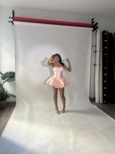 a woman in a pink dress is posing for a photo on a white backdrop with red bars