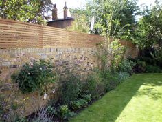 a brick wall in the middle of a garden with flowers growing on it's sides