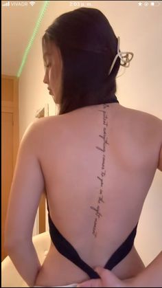 the back of a woman's body with writing on her upper and lower back