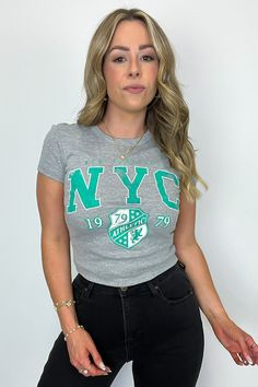 Details: Add some athletic flair to your wardrobe with our NYC Athletic Graphic Tee. With a short sleeve, fitted design and micro-ribbed fabric, this cropped tee is both comfortable and stylish. Perfect for any workout or casual day out in the city. - "NYC Athletic" graphic - Short sleeves Content: 90% COTTON 10% POLYESTER Size + Fit Model is 5'4" and wearing a Small Measurements from a size Small are approx. - Full length: 18" - Chest: 30" - Waist: 28" - Sleeves: 5" Brand: Sweet Claire Trendy Stretch Cropped T-shirt For Sports, Casual Cropped T-shirt For Workout, Short Sleeve Cropped T-shirt With Graphic Print For Sports, Athleisure Stretch T-shirt With Letter Print, Sporty Fitted Crop Top T-shirt, Sporty Letter Print Crop Top T-shirt, Sporty Cropped T-shirt For Spring Workout, Basic Stretch Cropped T-shirt For Streetwear, Sporty Stretch Cropped T-shirt With Graphic Print