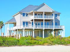 a large white house sitting on top of a sandy beach