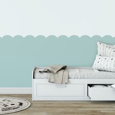 a white daybed with storage drawers in front of a blue wall and wooden floor