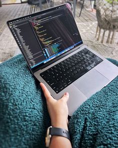 a person is using a laptop computer on a blanket in an outdoor patio area with tables and chairs