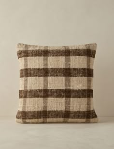 a brown and white checkered pillow sitting on top of a table