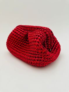 a red woven bag sitting on top of a white table next to a black object