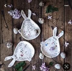 two white plates with flowers and eggs on them sitting on a wooden table next to each other