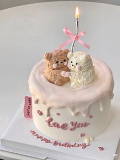 a birthday cake with two teddy bears on it and a candle in the shape of a heart