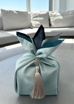 a blue bag with a tassel on it sitting on a table in front of a couch