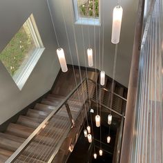 an overhead view of a staircase with several lights hanging from the ceiling and two windows above it