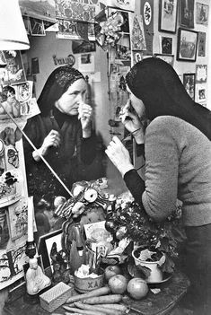 two women sitting at a table in front of a mirror with pictures on the wall