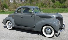 an old gray car parked in a parking lot