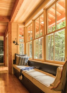 a living room filled with furniture next to a wooden wall and window covered in lots of windows