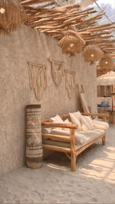 a couch sitting in the middle of a room under some straw umbrellas and lights