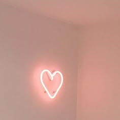 a heart - shaped neon sign on the wall in a room with a bed and nightstand