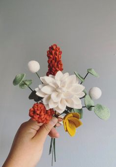 a hand is holding a fake flower arrangement