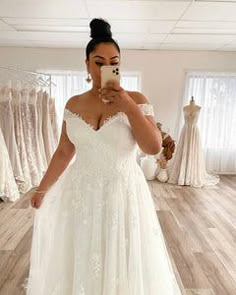 a woman is taking a selfie in her wedding dress while looking at her phone