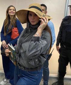 a woman with a hat on talking on her cell phone while standing next to police officers