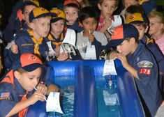 children in navy uniforms standing around an inflatable pool