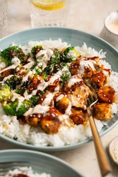 a blue plate topped with meat and broccoli covered in gravy next to rice