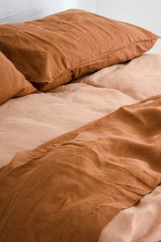 an unmade bed with brown sheets and pillows