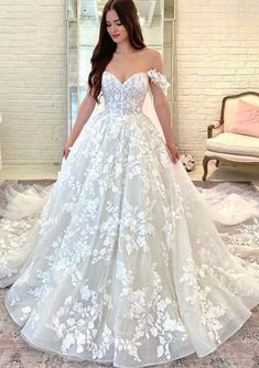 a woman standing in front of a mirror wearing a wedding dress with flowers on it