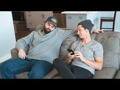 two men sitting on a couch looking at their phones