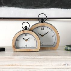 two clocks sitting on top of a white table