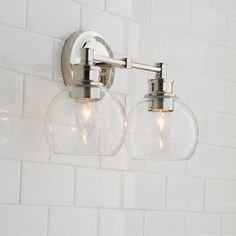 two clear glass globe lights on a white tiled wall