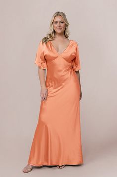 a woman in an orange dress posing for the camera with her hands on her hips