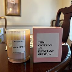 a candle sitting on top of a wooden table next to a box that says, this contains an important question