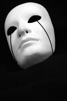 a white mask with black lines on it's face is shown in the dark