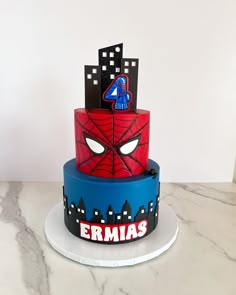 a three tiered cake decorated with spiderman faces and the number four on top