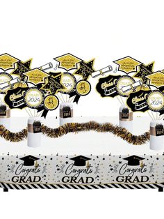 graduation decorations are on display in front of a white backdrop with black and gold confetti