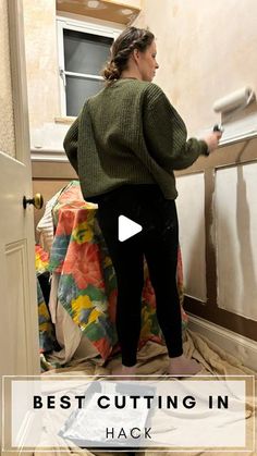 a woman is painting the walls in her home with paint rollers and she has a green sweater on