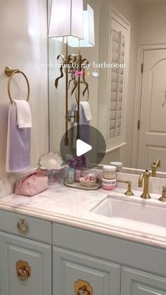 a bathroom sink sitting under a mirror next to a white counter top with gold faucets