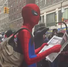 a person in a spiderman costume reading a newspaper