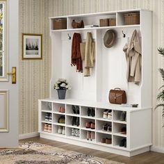 an entryway with a bench, coat rack and shoes on the floor next to a potted plant